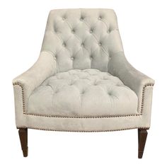 an upholstered white chair with wooden legs and nail polishing on the armrests