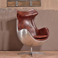 an egg chair sitting on top of a wooden floor next to a wall and window