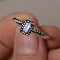 a close up of a person holding a ring with an amethyst stone in it