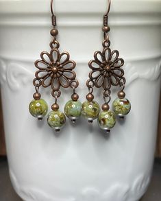 Beautiful copper flowers scented with soft sage green Czech glass Picasso beads and small copper round beads.  These earrings hang about 2 inches and are 3/4 inch wide.  The earwires are also copper. Bohemian Green Flower Earrings With Dangling Beads, Bohemian Green Flower Earrings With Round Beads, Adjustable Green Chandelier Earrings With Dangling Beads, Green Dangling Bead Flower Earrings, Green Dangle Flower Earrings With Beads, Bronze Copper Beaded Dangle Earrings, Green Flower Drop Earrings With Dangling Beads, Bronze Copper Dangle Beaded Earrings, Green Dangle Earrings With Dangling Beads