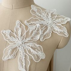 the back of a woman's dress with white lace flowers and leaves on it