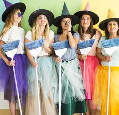 the girls are dressed up as witches and holding brooms in front of their faces