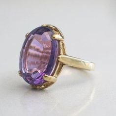 Amethyst is a gem with a very long history, it was even worn by St. Valentine, the patron saint of romance, by Leonardo Da Vinci who believed it would quicken his intelligence, and today it is the birthstone for the month of February. This Amethyst ring for sale features a large oval cut stone in a 14k gold setting. The setting of the ring has four prongs and delicate details that allows the brilliant purple gemstone to stand out! Metal: 14K Yellow GoldAmethyst: 16 x 12 MMSize: 3.5 If you have a Purple Gemstone Ring, Oval Amethyst Ring, Aqua Ring, Beautiful Rings Vintage, St Valentine, Woman Jewelry, Amethyst Gem, Ring Ideas, Long History