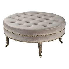 an upholstered round ottoman with gold studded trimmings on the legs