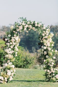 an outdoor wedding ceremony with white flowers and greenery