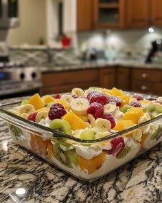 a glass bowl filled with fruit salad on top of a kitchen counter next to an oven