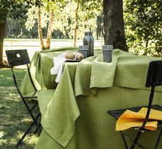 an outdoor table set up with two chairs and a green cloth draped over the table