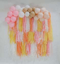 balloons and streamers are arranged on a white tablecloth with pastel orange, pink, yellow, and beige colors