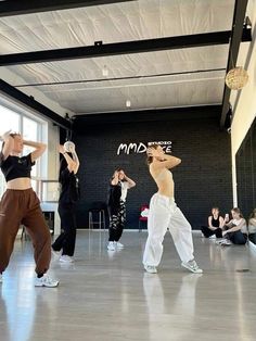 some people are dancing in a large room with graffiti on the wall behind them and one person is holding his head up