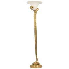 a gold colored floor lamp with a white glass shade on the top and a metal base