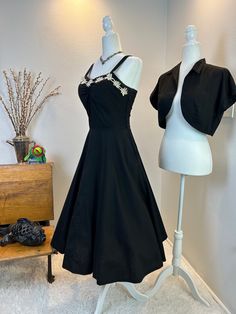 1950's Black Cotton Dress and Bolero / 1950s dress set / 50s dress set / 1950s sundress / 50s sundress / Rhinestone Flowers and bolero  This might just be the best late 1940s early 1950's set I have had in the shop to date! She is absolutely fantastic and perfect for summer. The sundress and bolero are made firm the same black cotton. The bodice it ruched in the middle and is adorned with flowers and rhinestonesz. The dress has a center metal zipper, a nipped waist and a full skirt.  The bolero matches the dress and has a wide waist tie that can be tied several different ways. Both items  are still their original dark black, don't have any color fade and have their makers tags, Jane Evan's which proves them to be an original set.  Measurements provided are flat and have been doubled. dress 1950s Style Vintage Fashion Dresses, 1950s Style Vintage Dress For Vintage Events, Fitted 1950s Style Vintage Dress For Vintage Events, 1950s Style Vintage Dress With Fitted Bodice, 1950s Style Vintage Tea Length Evening Dress, 1950s Tea Length Vintage Dress For Events, 1950s Tea Length Vintage Style Dress, 50s Sundress, 1950s Sundress