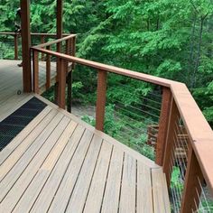 a wooden deck with metal railings and trees in the background