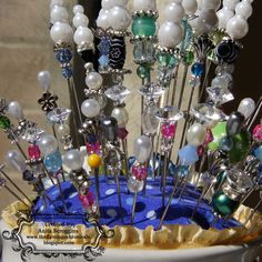 a bowl filled with lots of different types of pins and beads on top of a table