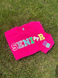 Class of 2025 Senior T-Shirt or Sweatshirt with Chenille Patches Celebrate your senior year in style with our Class of 2025 T-Shirt or Sweatshirt, featuring classic chenille patches for a unique and trendy look. This standout piece is perfect for showcasing your school spirit and marking this special milestone. Features: *Design: "Senior" in chenille patches on the front, giving a retro yet fashionable vibe. Available with a cute bow in place of the O (also available without the bow): "25" featu Diy Senior Sweatshirt, Sweatshirt Patches Ideas, Senior 25 Shirts, Diy Senior Sweatshirts Ideas, Fun Senior Year Ideas, Senior Sweatshirts Ideas Diy Patches, Senior Year Shirts Design 2025, Senior Hoodies Diy, Varsity T-shirt With Letter Embroidery For College