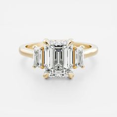 an emerald cut diamond ring with three baguets in yellow gold and white diamonds