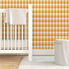 a white crib in front of a yellow checkered wall with a trash can next to it