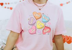 Looking for a unique Valentine's Day gift? Look no further than our Comfort Colors Conversation Hearts Shirt!  The shirt features colorful candy hearts, and it makes the perfect shirt to wear on Valentine's Day or any day you want to show your affection for someone special. Plus, the shirt is made from high quality materials that will make it last long and be comfortable to wear.  Comes in multiple colors! ✨️SIZE AND FIT: Your shirt will be printed on a high-quality, soft and comfortable unisex Trendy Tops With Heart Graphic For Gift, Pink Heart-shaped Top For Valentine's Day, Cute Multicolor Heart-shaped Tops, Playful Graphic Print T-shirt For Valentine's Day, Cute Heart Print T-shirt For Valentine's Day, Valentine's Day Gift T-shirt With Heart Graphic, Playful Valentine's Day Crew Neck T-shirt, Heart-shaped Pink Top For Valentine's Day, Fun Letter Print T-shirt For Valentine's Day