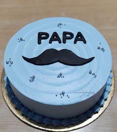 a blue cake with a mustache on it that says papa written in black and white