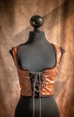 a mannequin wearing a brown leather top with laces on the front and sides