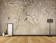 an empty room with a tree and birds painted on the wall, next to a lamp