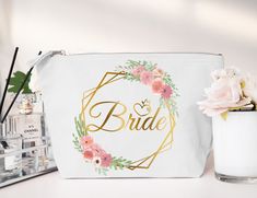 a white cosmetic bag with the word bride written on it and flowers in front of it