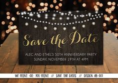 save the date sign on top of a wooden table with string lights in the background