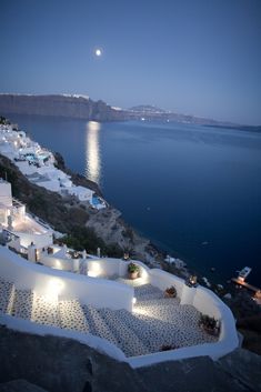 an aerial view of the sea and white buildings at night, with lights on them