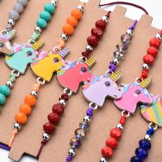 several necklaces with different colored beads and charms on top of a piece of cardboard