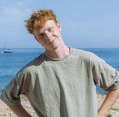 a man with red hair standing by the ocean