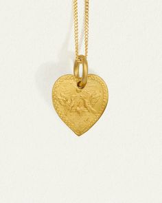 Graced with eagle reliefs on both sides, this solid gold heart necklace embodies bravery and love. The design draws inspiration from the Latin word for heart, originally signifying the courageous expression of one's true feelings.  
 Crafted from 24k solid gold, this double-sided pendant exudes a rich, tactile lustre that enhances its allure. A 14k yellow gold curb chain completes the Courage Necklace. Symbolic Engraved Heart Pendant Necklaces, Symbolic Engraved Heart Pendant Necklace, Symbolic Heart Pendant Necklace Engraved, Gold Necklace With Large Heart Pendant, Tarnish Resistant Yellow Gold Heart Pendant Necklace, Symbolic Yellow Gold Heart Pendant Jewelry, Symbolic Yellow Gold Heart Pendant Necklace, Symbolic Yellow Gold Heart Jewelry, Spiritual Yellow Gold Necklace With Heart Charm