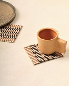 a coffee cup sitting on top of a place mat next to a plate and spoon