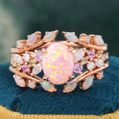 an opal and diamond ring sits on top of a blue velvet cushion