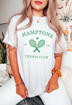 Elevate your tennis style with our exclusive Hamptons Tennis Club shirt featuring crossed tennis rackets at the center and the iconic tennis club logo beneath. This premium tennis apparel combines classic Hamptons elegance with the sporty spirit of tennis. 🎾 Key Features: ✨ Premium Quality: Crafted with the finest materials for ultimate comfort and durability. 👕 Stylish Design: Crossed tennis rackets symbolize your passion for the game, while the Tennis Club logo adds authenticity. 🌞 Perfect for the Hamptons: Show your Hamptons pride on and off the court with this sophisticated tennis shirt. 🎁 Great Gift Idea: Ideal for tennis enthusiasts and Hamptons aficionados. Discover more Hamptons tennis fashion and exclusive designs on our Shop page. Get ready to ace your style game with Hampton Cotton Short Sleeve T-shirt For Tennis, White Graphic Tennis T-shirt, Short Sleeve Summer Tennis Tops, Short Sleeve Tennis Tops For Summer, Summer Tennis Tops With Short Sleeves, Summer Short Sleeve Tennis Tops, Summer Cotton Tennis Tops, Cotton Tennis Tops For Summer, Sporty Screen Print T-shirt For Tennis