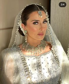 a woman in a wedding dress with pearls on her head and veil over her face