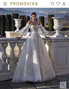 a woman in a wedding dress standing on a balcony with her hands on her hips