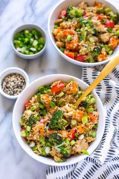 two bowls filled with rice and vegetables on top of a white table cloth next to small bowls