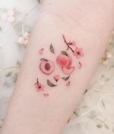 a woman's arm with an apple and flower tattoo on it