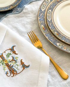 the table is set with white linens and gold colored utensils