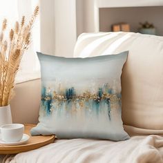 a blue and white pillow sitting on top of a couch next to a coffee cup