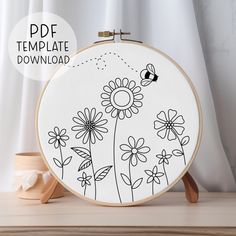 an embroidery pattern with flowers and a bee on it