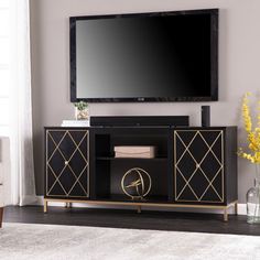 a black and gold entertainment center with a flat screen tv mounted on it's wall