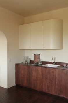 an empty kitchen with wooden floors and cabinets