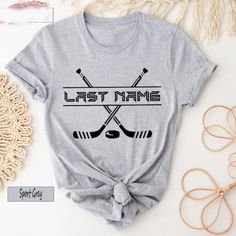 a t - shirt that says last name and two crossed hockey sticks