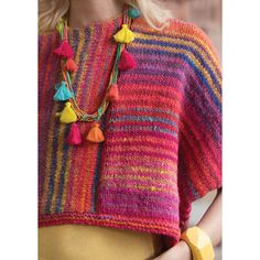 a woman wearing a multicolored sweater with tassels and a yellow necklace