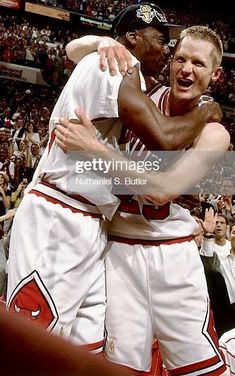 two basketball players hugging each other in front of an audience