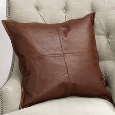 a brown leather pillow sitting on top of a white chair