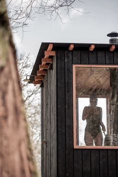 a woman standing in the window of a small building with a mirror on it's side