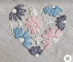 a heart made out of flowers on a piece of fabric with the word love written in it