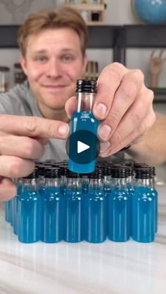 a man is holding a blue bottle and pointing to it