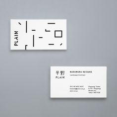 two business cards sitting next to each other on top of a gray surface with black and white lettering